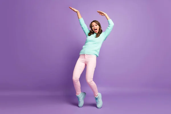 Foto de cuerpo completo de la señora divertida escalofriante levantar las manos bailando movimientos modernos estudiantes locos usar casual mullido jersey pastel pantalones rosados zapatos aislados color púrpura fondo —  Fotos de Stock