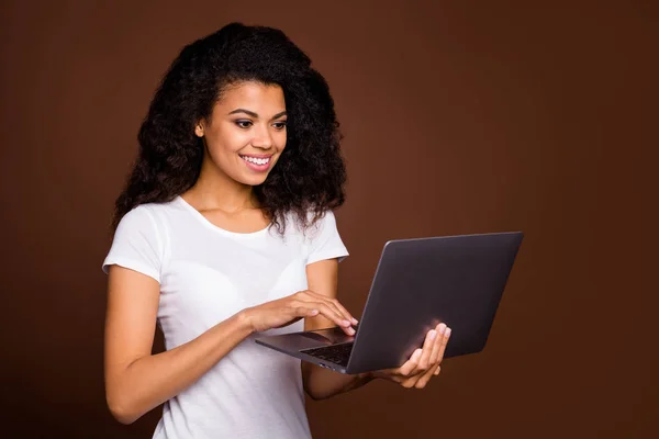 Portrait of positive cheerful afro american girl using computer search read social media news wear casual style clothes isolated over brown color background — Stok Foto