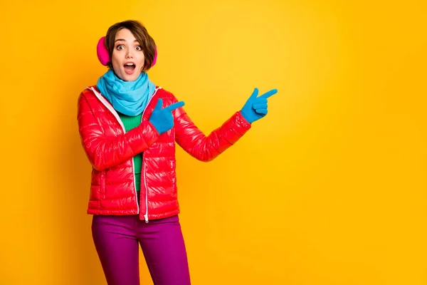 Φωτογραφία από αστεία κυρία ανοιχτό στόμα δείχνουν δάχτυλα κενό χώρο τελευταία σεζόν χαμηλές τιμές φορούν casual κόκκινο παλτό μπλε κασκόλ γάντια αυτί θερμαίνει παντελόνι απομονωμένο κίτρινο χρώμα φόντο — Φωτογραφία Αρχείου