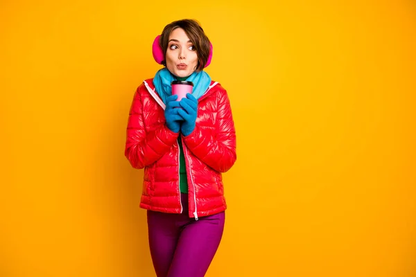 Photo of funny pretty lady holding paper cup hot takeout coffee warming cold day wear casual red coat blue scarf gloves ear covers pants isolated yellow color background — 图库照片