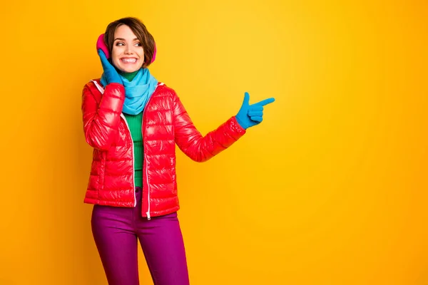 Boş uzay dokunuşu yapan komik kadının fotoğrafı modern pembe kulaklıklar giyer sıradan kırmızı palto giyer mavi eşarp eldivenler takar pantolon sarı arka plan izole edilir — Stok fotoğraf