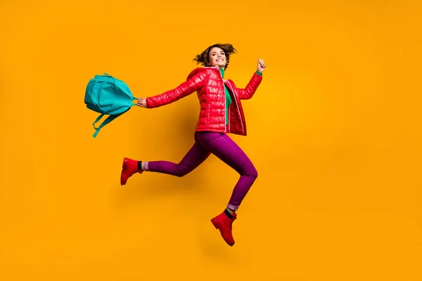 Tam boy profil fotoğrafı neşeli funky genç kız atlama kolej çalışma günü mavi sırt çantası mor parlak moda kıyafetler giyin kırmızı çizmeler izole edilmiş sarı arka plan — Stok fotoğraf