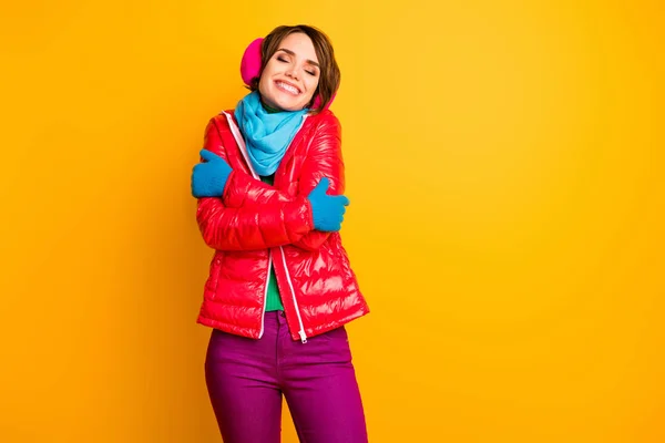 寒い寒い天気で暖かいコートを楽しむ素晴らしい女性の写真抱擁彼女自身はスタイリッシュなカジュアルショートレッドオーバーコートブルースカーフ手袋耳フパンツ孤立黄色の色の背景を身に着けている — ストック写真