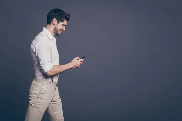 Profile side photo of imposing positive guy go walk use cellphone chatting with friends reading social media news wear stylish clothing isolated over grey color background — 스톡 사진