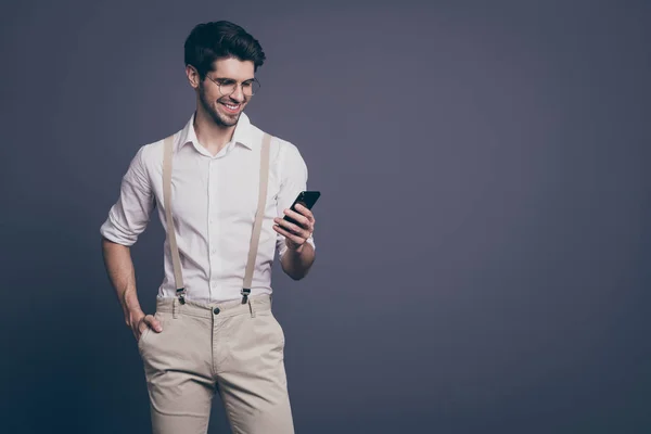 Photo of successful business man good mood holding telephone hands read work email dressed formalwear shirt suspenders trousers specs isolated grey color background — 스톡 사진