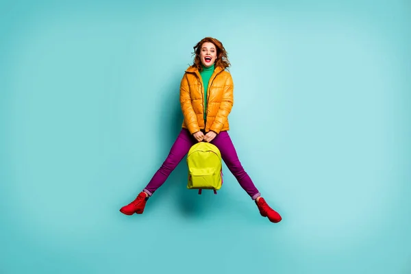 Фотографія красивої леді, яка стрибає високо радісно після уроків коледжу, тримає шкільну сумку, одягнену в пальто штани з фалантом, червоний взуття одяг ізольований сльозогінний кольоровий фон — стокове фото