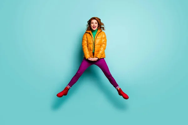 Full length photo of beautiful lady model jump high up relaxicing spread legs wear yellow coat magenta pants πράσινο ζιβάγκο κόκκινο υπόδημα ρούχα απομονωμένο teal χρώμα φόντο — Φωτογραφία Αρχείου