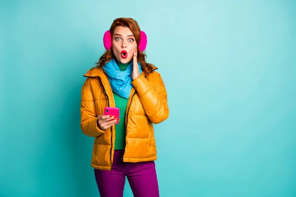 Foto de señora viajera divertida sostener teléfono boca abierta comprobar seguidores no creer ojos brazo en mejilla usar abrigo amarillo bufanda púrpura pantalones aislados color verde azulado fondo — Foto de Stock