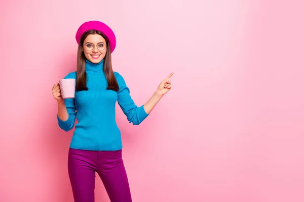 Portrait of positive girl promoter hold cup with caffeine cappuccino point index finger direct way to cafeteria wear blue pants isolated over pink pastel color background — ストック写真