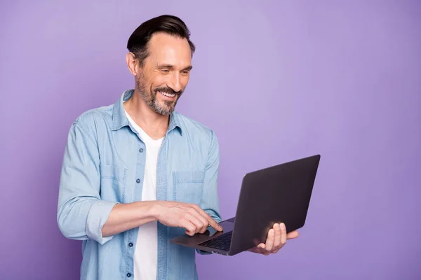 Portrait of positive cheerful man use computer for work make project read information document feel he real successful worker wear good looking outfit isolated over violet color background — Stockfoto