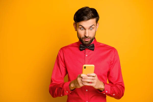 Photo of attractive business guy hold telephone social network worker reading good news growth blog popularity wear trendy red shirt bow tie isolated yellow color background — 图库照片
