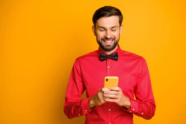 Photo of attractive business guy hold telephone social network worker writing advertisement creative designer wear trendy red shirt bow tie isolated yellow color background — ストック写真