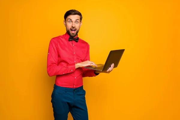 Photo of attractive business guy worker hold notebook read corporate email good news wear trendy red shirt with black bow tie blue pants isolated yellow color background — Zdjęcie stockowe