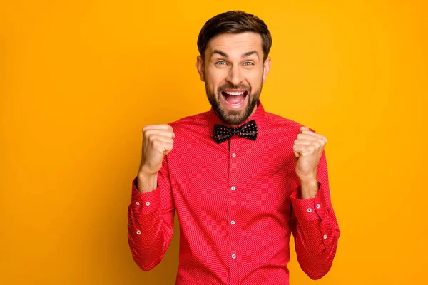 Photo of funny macho guy good mood open mouth celebrating lottery money winning raise fists excited wear stylish red shirt with black bow tie isolated yellow color background — Stockfoto