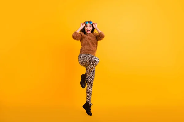 Foto de cuerpo completo de la señora funky saltando de buen humor de alta juventud mirada adicto comprador tomando sol especificaciones de usar suéter esponjoso pantalones de leopardo botas aisladas de color amarillo de fondo —  Fotos de Stock