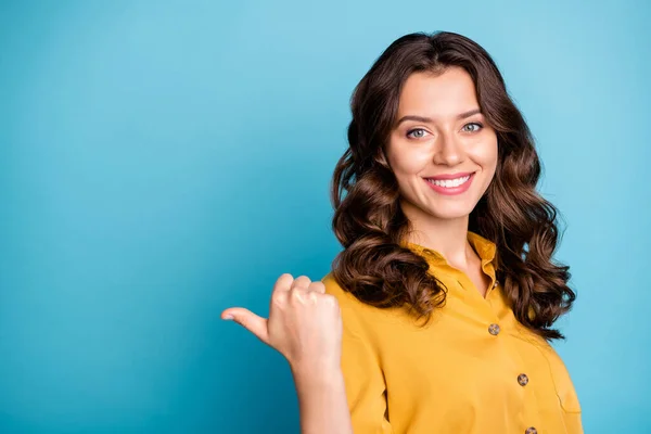 Photo of charming business manager lady indicating thumb finger empty space advising new product low price wear yellow shirt isolated blue color background — 图库照片