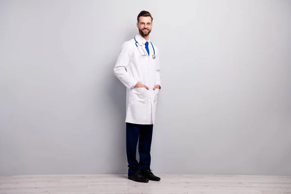 Full length body size view of his he nice attractive cheerful cheery doc expert first aid new innovative assistance center holding hands in pockets isolated on light white gray pastel color background