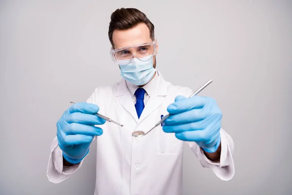 Close-up portrait of his he nice attractive experienced qualified doc dentist holding in hands steel instrument preparing surgery isolated on light white gray pastel color background — Stock Photo, Image