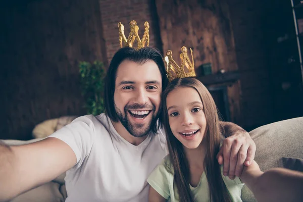 Primeros planos de la pequeña señora divertida su guapo papá amistad sentarse cómodo sofá haciendo selfies abrazo desgaste coronas de oro celebridades famosa persona casa habitación interior — Foto de Stock