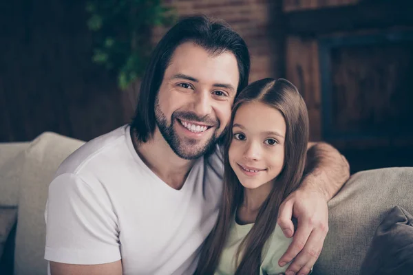 Photo of beautiful little adorable lady her handsome young daddy sit comfy sofa hugging dreamy smile spend weekend time homey domestic house room indoors — Stock Photo, Image