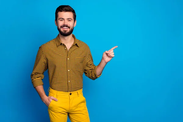 Pozitif neşeli erkek organizatörünün portresi işaret parmağı kopyalama alanı reklamların tanıtımını gösteriyor ki mavi arkaplan üzerine izole edilmiş şık damalı giysiler giyin — Stok fotoğraf