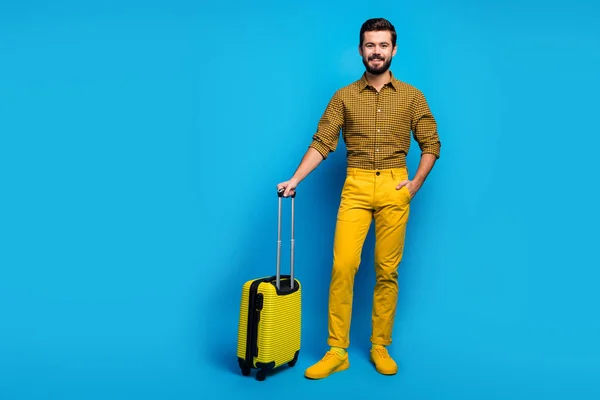 Full length photo of positive cheerful guy have big bright bag trolley enjoy tourism weekend wear good look trendy clothing gumshoes isolated over blue color background — 스톡 사진