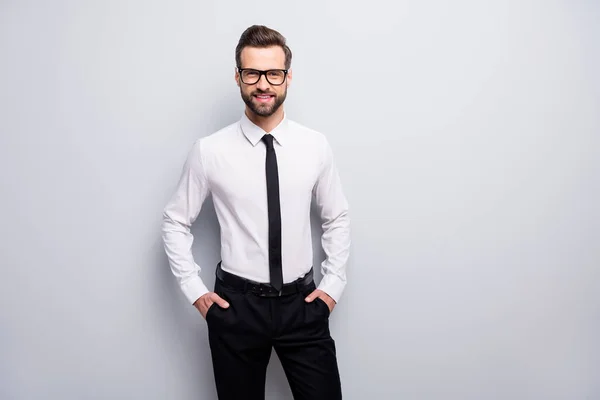 Foto di bello macho uomo d'affari dentato trave sorridente amichevole capo mani in tasche indossare specifiche bianco ufficio camicia nero pantaloni cravatta isolato colore grigio sfondo — Foto Stock