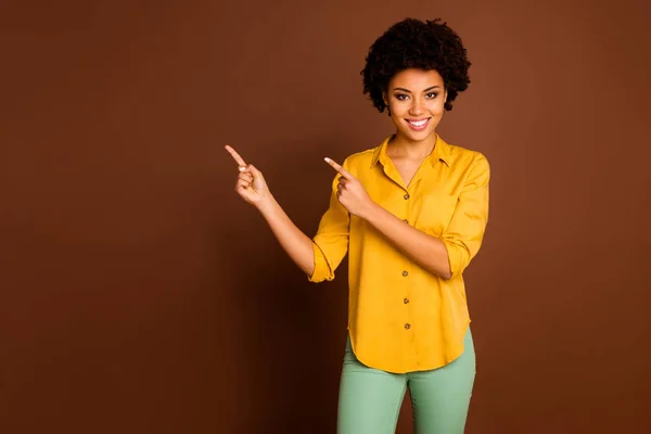 Πώληση. Φωτογραφία από όμορφο αρκετά σκούρο δέρμα κυματιστή κυρία δείχνει δάχτυλα κενό χώρο απολαύσετε την πώληση τιμές των αγορών φορούν κίτρινο πουκάμισο πράσινο παντελόνι απομονωμένο φόντο καφέ χρώμα — Φωτογραφία Αρχείου