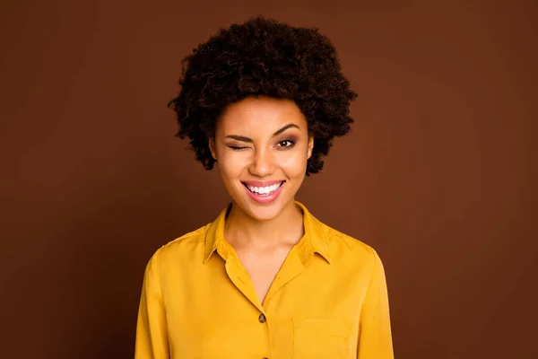 Foto de primer plano de la divertida hermosa piel bastante oscura dama ondulada buen humor positivo coqueto parpadeo un ojo desgaste camisa amarilla blusa aislado color marrón fondo — Foto de Stock