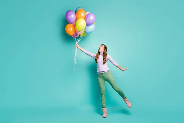 Full length profile photo of pretty crazy lady hold many colorful air balloons fly away with wind blowing wear lilac jumper green pants shoes isolated teal pastel color background — 스톡 사진