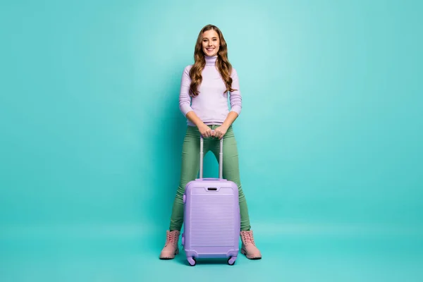 Volledige foto van vrij grappige dame kwam luchthaven met rollende reis geval kiezen beste luchtvaartmaatschappijen dragen lila trui groene broek schoenen geïsoleerde teal pastel kleur achtergrond — Stockfoto
