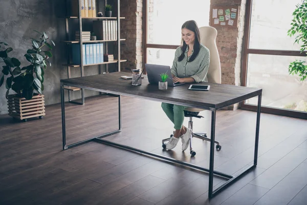 Foto von attraktiven lateinamerikanischen Business Lady gute Laune Notizbuch Tisch Chat Kollegen lesen Corporate Report tragen gestreifte Hemd sitzen Stuhl moderne Inneneinrichtung Büro drinnen — Stockfoto