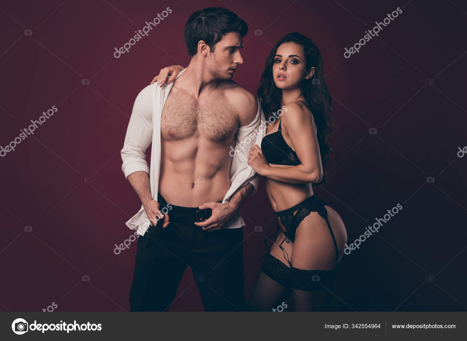 Photo of two hot people macho husband unfasten pants belt look at mistress bikini wife taking off his shirt enjoy submission role play game isolated maroon color background Stock Photo by ©deagreez1 picture