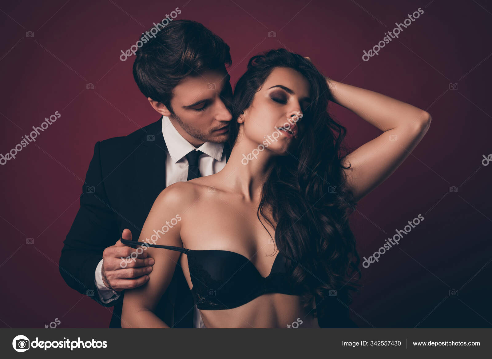Closeup photo of horny two people husband black suit nude wife ideal body stand close take off brassiere tempting wish kissing neck satisfaction isolated burgundy color background Stock Photo by ©deagreez1 342557430 pic
