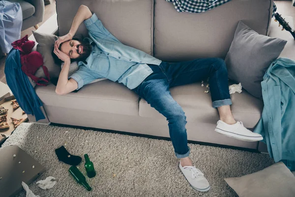 Профиль фото сумасшедшего хипстера, лежащего на диване с головой в бутылках из-под пищевого белья, лежащих на полу. У мальчишника вечеринка с похмельем. — стоковое фото
