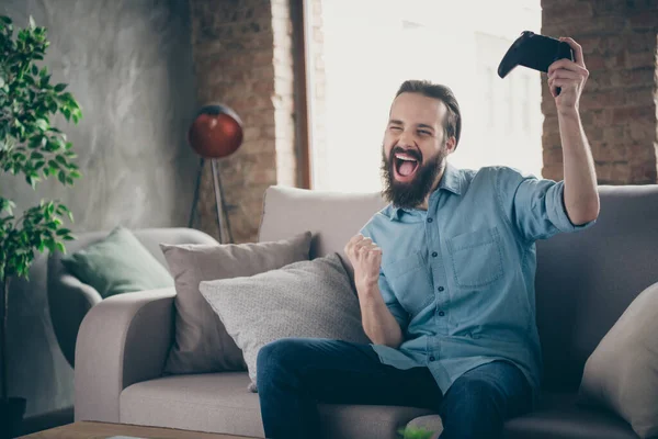 Portret van hem hij mooi aantrekkelijk vrolijk vrolijk dolblij gek brunet guy zitten op divan spelen online spel plezier op industriële loft moderne stijl interieur kamer huis binnen — Stockfoto