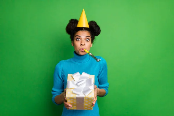 Φωτογραφία από funky παιδικό σκούρο δέρμα κυρία γενέθλια κρατήσει μεγάλα χέρια giftbox φυσώντας θόρυβο maker στο στόμα φορούν χαρτί κώνο καπέλο μπλε ζιβάγκο απομονωμένο πράσινο χρώμα φόντο — Φωτογραφία Αρχείου