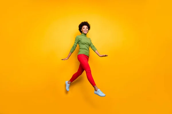 Full length body size turned photo of curly wavy brunette hair girl running jumping in red trousers white footwear isolated vivid color background — Stok fotoğraf