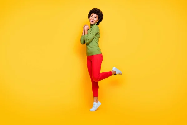 Turned full length body size photo of cheerful positive cute pretty nice girl in red pants trendy smiling toothily in white foot wear isolated vivid color background — 图库照片