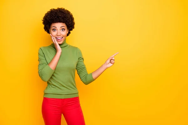 Foto de alegre novia positiva bastante dulce señalando en el espacio vacío con el dedo índice en pantalones rojos aislado fondo de color vivo — Foto de Stock