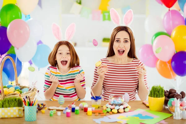 Portrait of two nice attractive ecstatic crazy creative cheerful cheery girls small little pre-teen sister wearing bunny ears having fun making craft in white light interior room house — Stockfoto