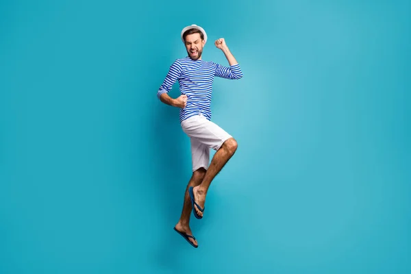 Full body profile photo of funky astonished guy tourist jump high celebrating vacation start wear striped sailor shirt vest cap shorts flip flops isolated blue color background — Stockfoto
