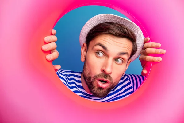 Zbliżenie zdjęcie podekscytowany zainteresowany zabawny facet turysta wygląd strony wewnątrz różowy guma float lifebooy zobacz sprzedaż zakupy nosić paski marynarz koszula czapka odizolowany niebieski kolor tło — Zdjęcie stockowe