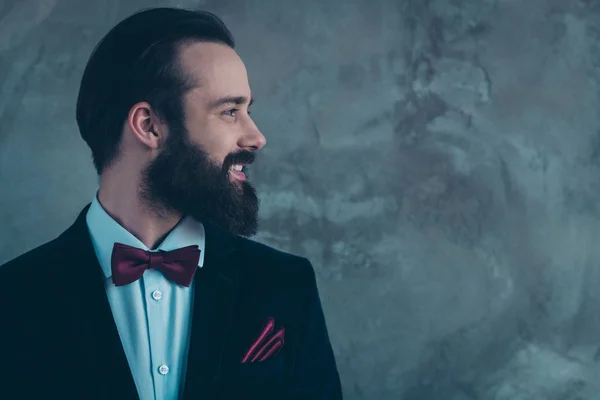 Close-up profile side view portrait of his he nice attractive classy cheerful cheery bearded guy wearing tuxedo for event isolated over gray concrete industrial wall background — ストック写真