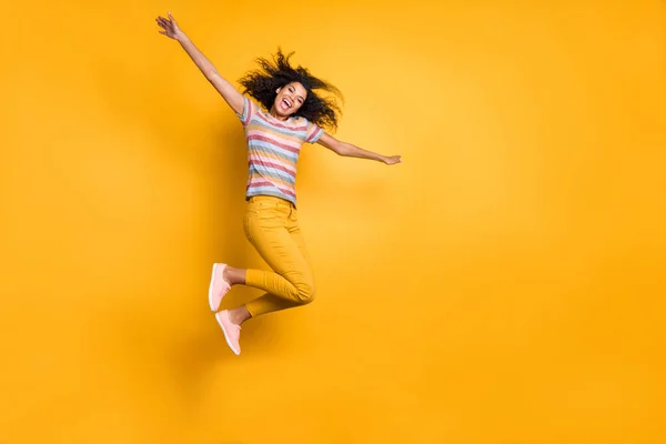 Full length body size view of nice attractive ecstatic carefree cheerful cheery golvy-haired girl in striped t-shirt jumping up flying isolated on bright vivid shine vibrant yellow color background — Stockfoto