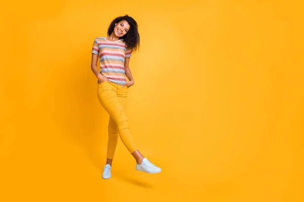 Longitud completa tamaño del cuerpo vista de agradable atractivo femenino encantador lindo alegre alegre chica de pelo ondulado en camiseta a rayas caminando posando aislado sobre brillante brillo vivo vibrante color amarillo fondo —  Fotos de Stock