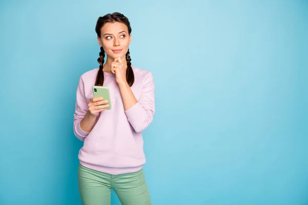 Foto van mooie dame met telefoon moderne gebruiker denken nieuwe blog post creatieve advertentie tekst dragen casual stijlvolle roze trui groene broek geïsoleerde blauwe kleur achtergrond — Stockfoto
