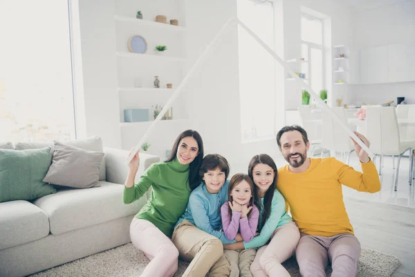 Retrato de agradável atraente perfeita alegre família três pré-adolescente crianças mãe pai sentado no tapete chão segurando na mão telhado sobre a cabeça boa mudança na luz branco interior estilo casa sala de estar — Fotografia de Stock