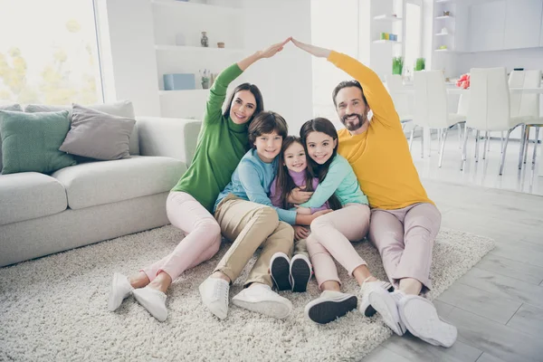 Retrato de agradável atraente alegre adorável ideal família três pré-adolescentes crianças mãe pai sentado no chão do tapete mostrando fazendo telhado boa mudança no conforto aconchegante luz branca interior estilo casa — Fotografia de Stock