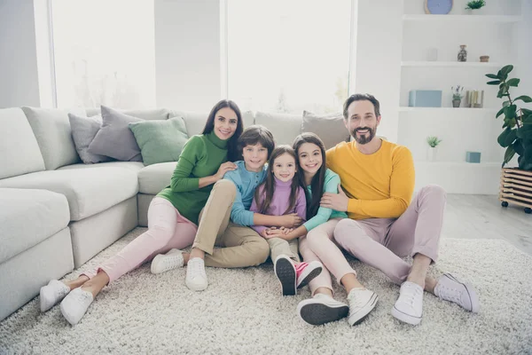 Портрет милої привабливої милої веселої дружньої сім'ї трьох дітей, що сидять на килимовій підлозі, що приймає свято в світло-білому інтер'єрі будинку житлової вітальні — стокове фото